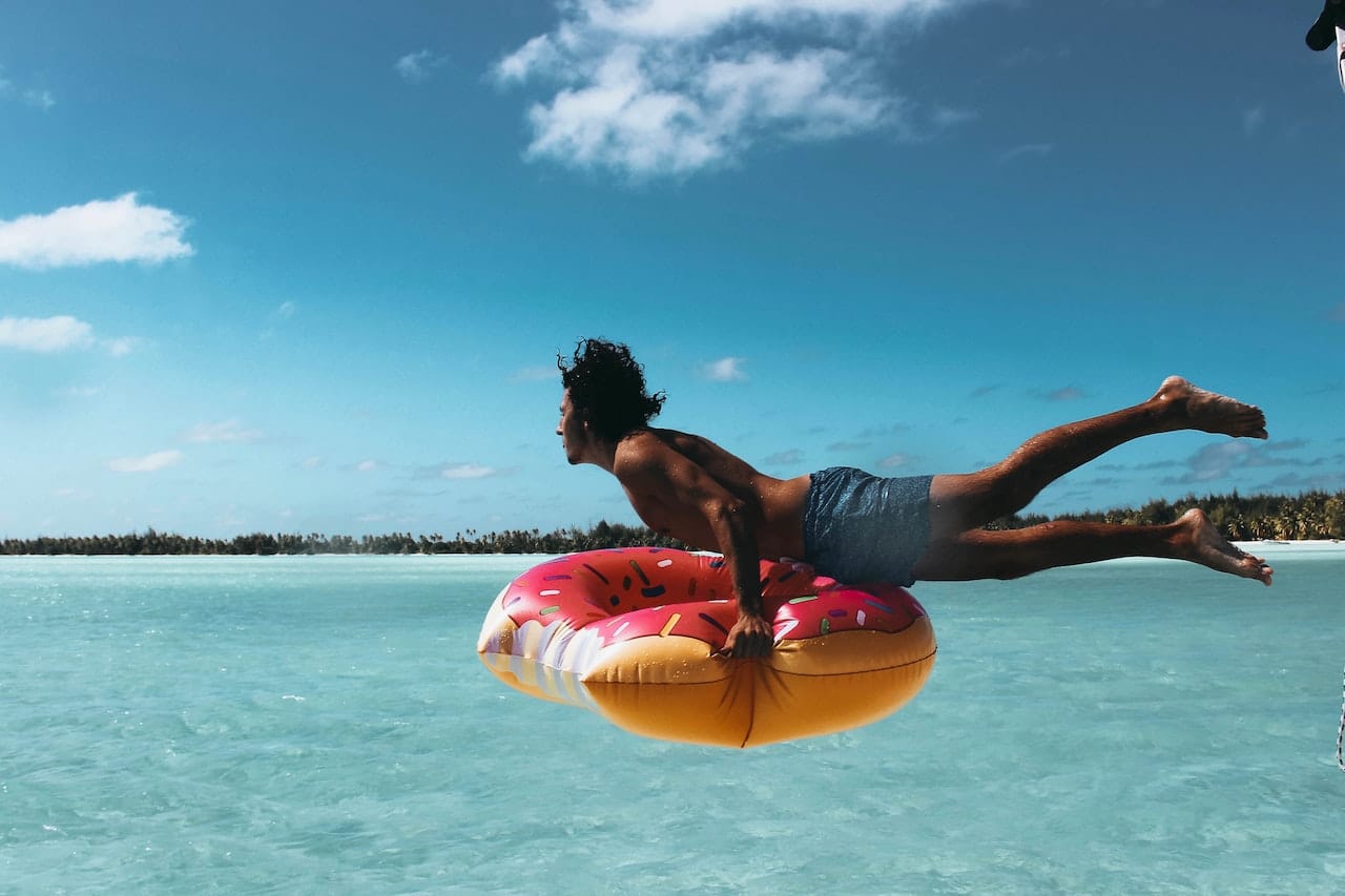 A man swimming in the ocean with inflatable donut ring.